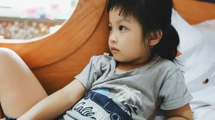 Çocuklarda karın ağrısı nedeniyle yatakta dinlenen çocuk