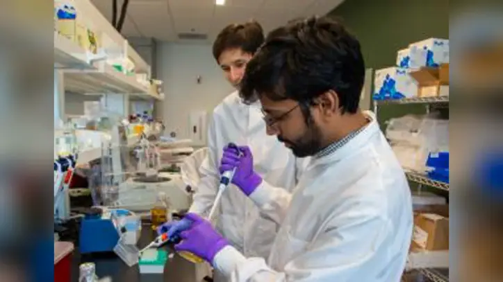 scientist in white lab coat pipetting sample into well