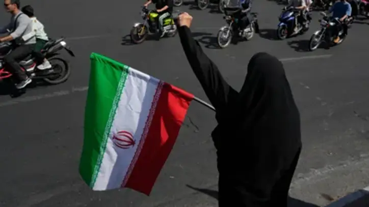 A woman chants slogan as she holds an Iranian flag while motorcyclists ride during a state-organized motorcycle parade called "Janfada," meaning "Sacrifice for Iran", in Tehran, Iran, Friday, Sept. 25, 2026. (AP)