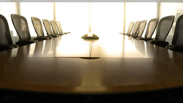 Empty conference room with a long wooden table, black office chairs on both sides, and large windows letting in natural light—ideal for law offices or meetings requiring litigation support.